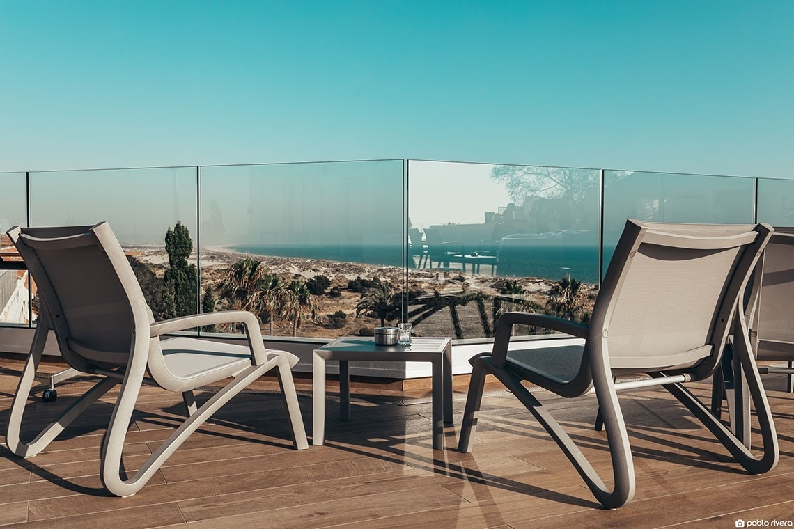 duas cadeiras e uma mesa em uma varanda com vista para o oceano