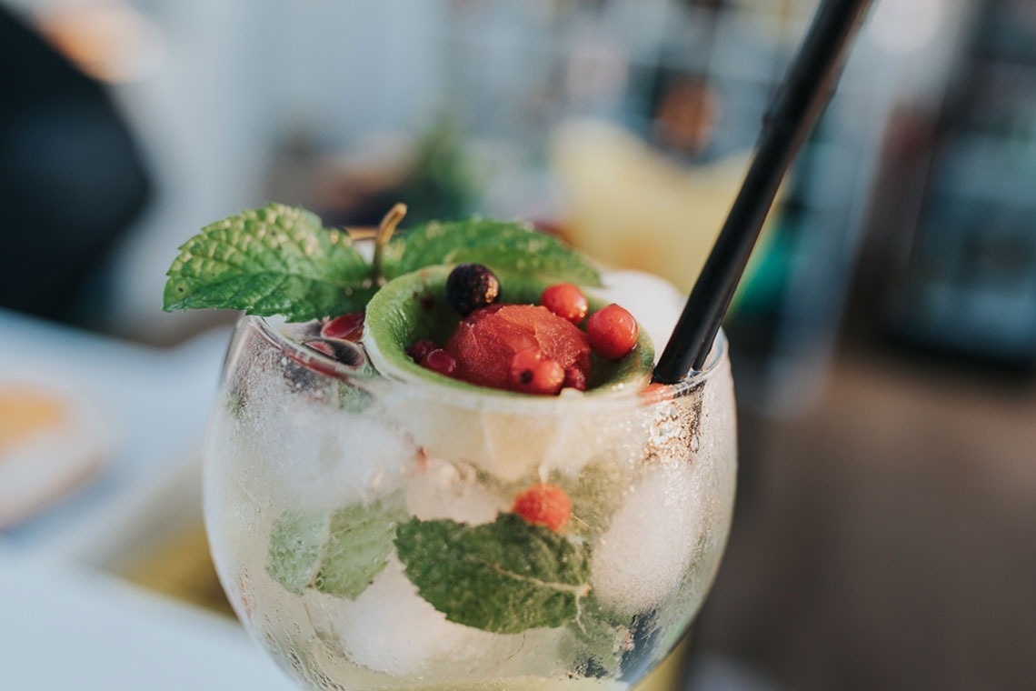 um copo de água com gelo e frutas e uma palha