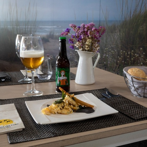 una mesa con un plato de comida y una botella de cerveza