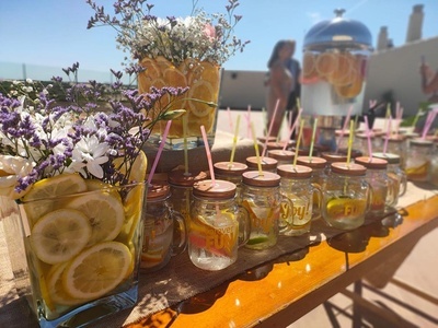 una mesa de madera cubierta de frascos de vidrio llenos de limones y bebidas - Celebraciones