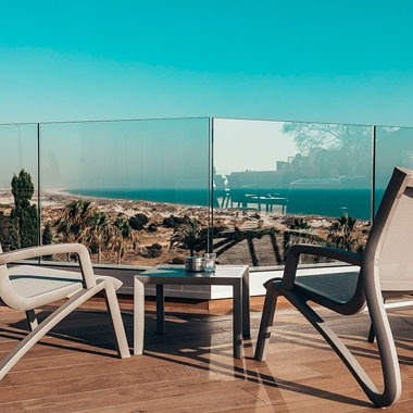 dos sillas y una mesa en un balcón con vista al océano .