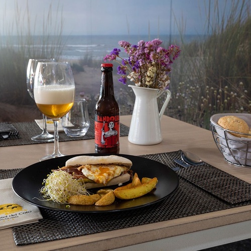 una mesa con un plato de comida y una botella de cerveza