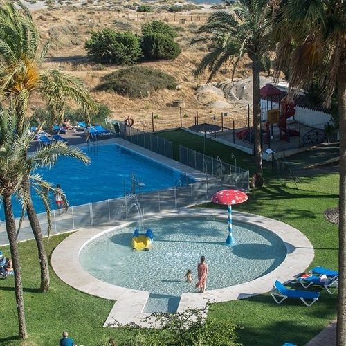 una mujer camina por una pequeña piscina rodeada de palmeras