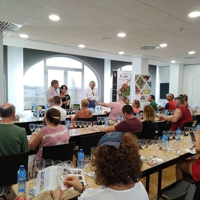un grupo de personas están sentadas en mesas con copas de vino