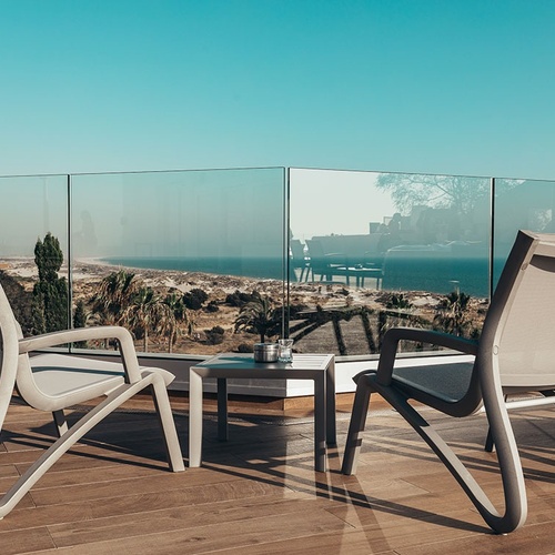 dos sillas y una mesa en un balcón con vista al océano