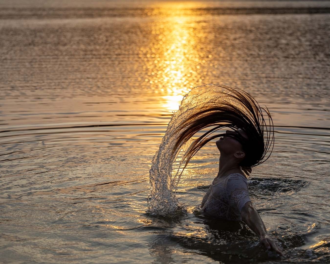 <p>Gran Hotel del Coto: mujer en el agua con cabello y agua salpicando al atardecer.</p>
