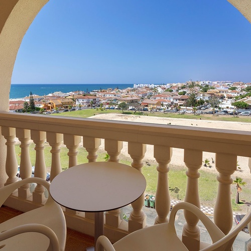 una mesa y sillas en un balcón con vista al océano