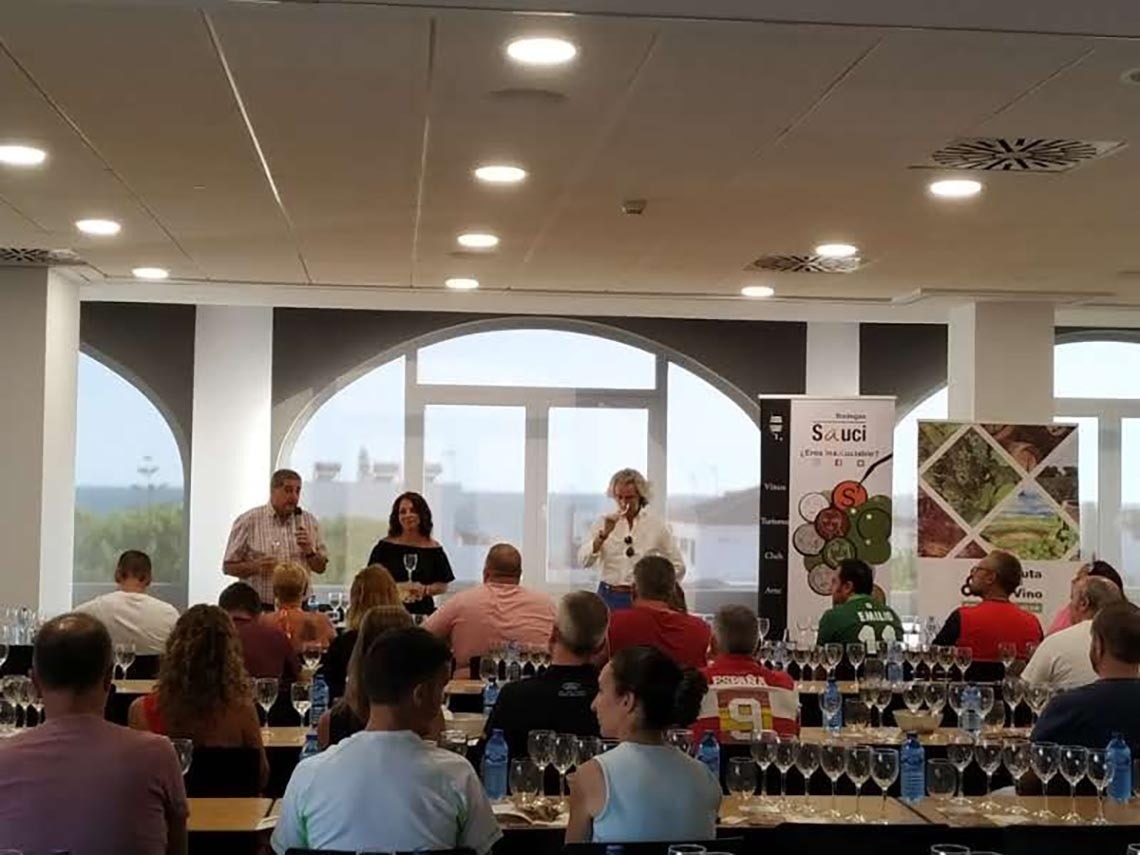 un grupo de personas en una habitación con un cartel que dice sauci