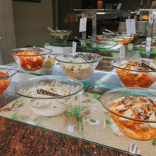 una variedad de ensaladas están sobre un mostrador de vidrio