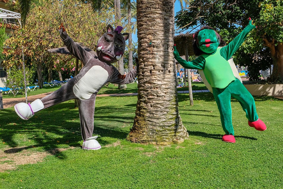 un hipopótamo y una tortuga se paran junto a una palmera
