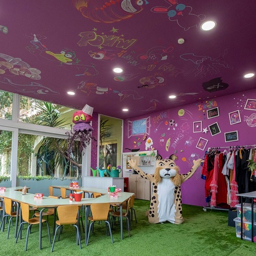 una sala de juegos con paredes moradas y una mascota de leopardo