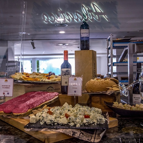 una mesa de comida con una botella de miguel en primer plano