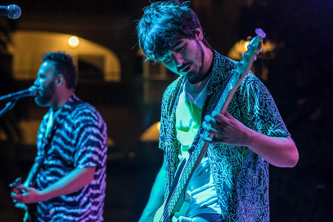 un hombre toca la guitarra mientras otro canta en el micrófono