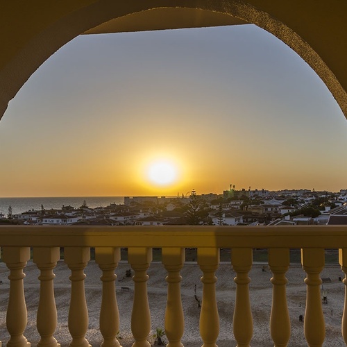 una vista del atardecer desde un balcón con una barandilla