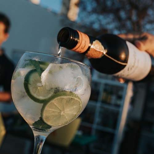 una botella de vino se vierte en un vaso con hielo y rodajas de limón