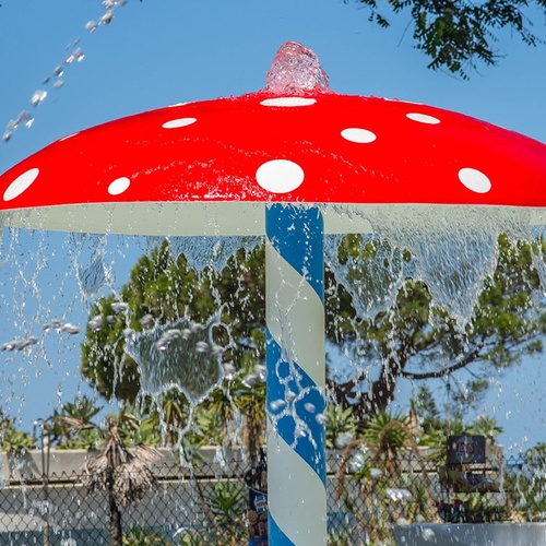 una fuente de agua en forma de hongo rojo y blanco