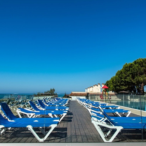 una fila de tumbonas azules y blancas junto a una piscina