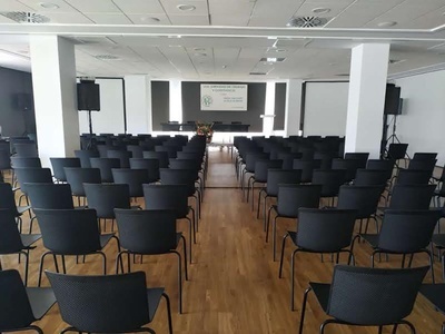 una sala de conferencias llena de sillas negras - MICE