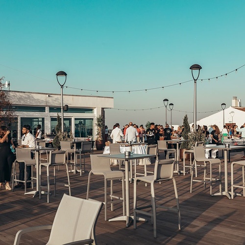 un grupo de personas se reúnen en un patio con mesas y sillas