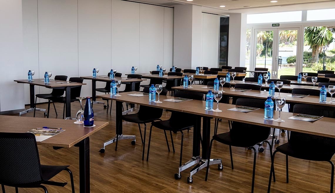 una sala de conferencias con mesas y sillas y botellas de agua