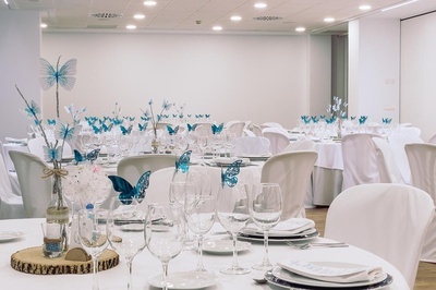 una mesa llena de copas de vino y mariposas azules - Celebraciones