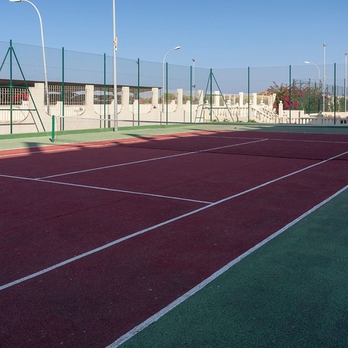 una cancha de tenis con una red verde y una pista roja