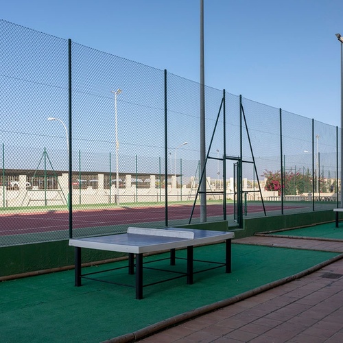 una mesa de ping pong está al lado de una cancha de tenis