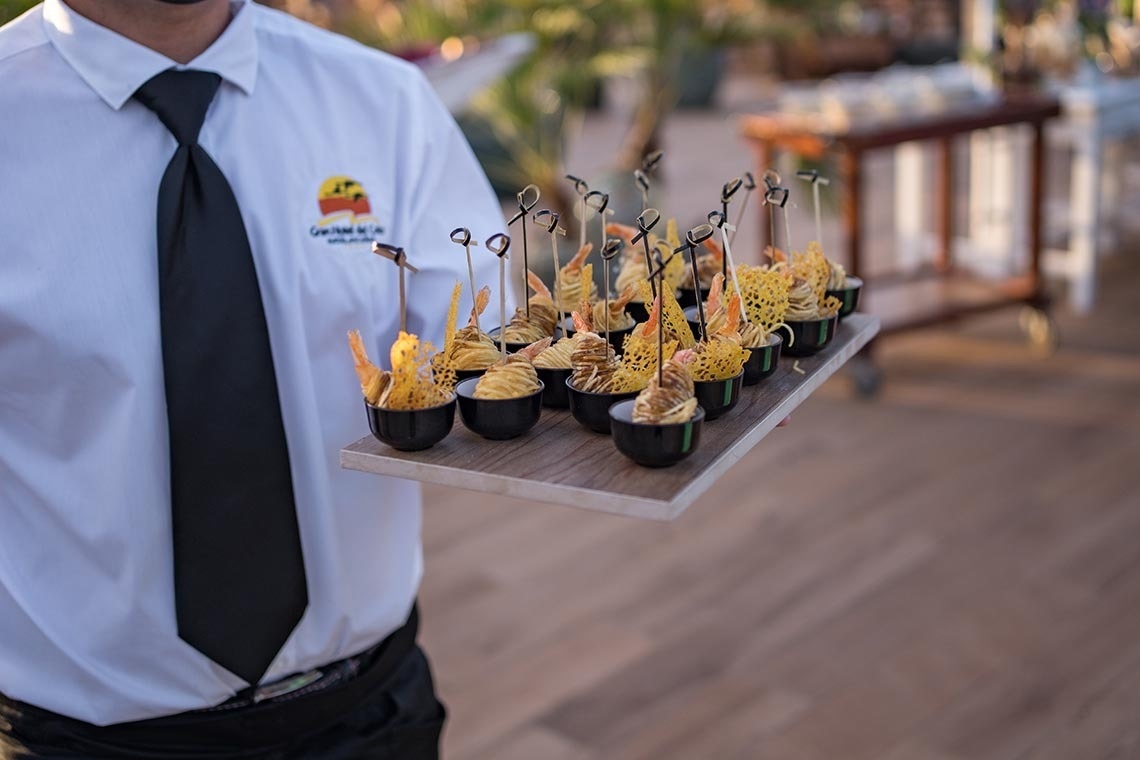 un hombre con una camisa blanca y corbata negra sostiene una bandeja de comida