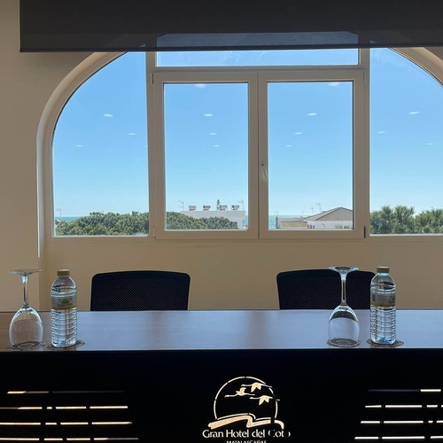 una mesa con botellas de agua y copas frente a una ventana del gran hotel del sol