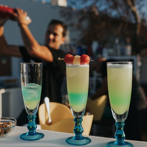 un barman prepara un cóctel con una sandía encima