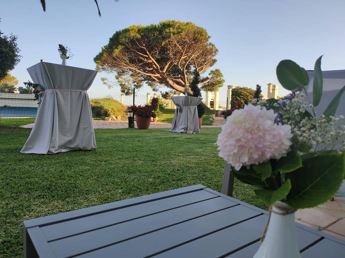 un jarrón de flores se sienta en una mesa al aire libre