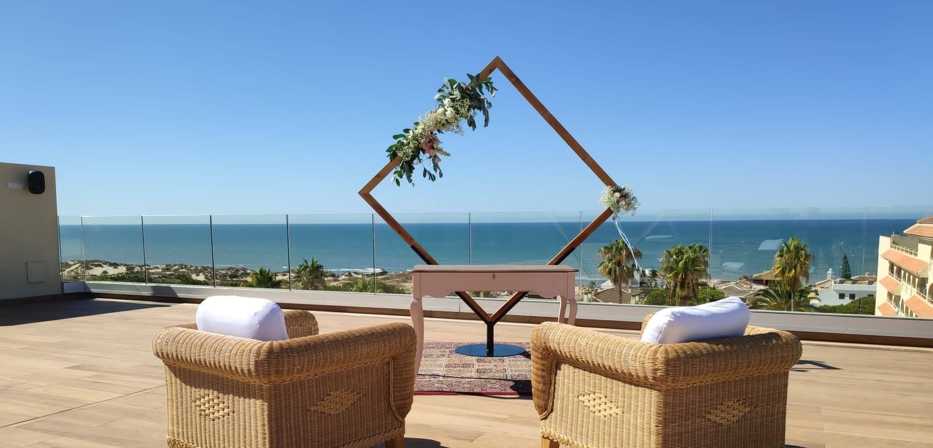 dos sillas de mimbre están frente a un arco de madera con flores en él