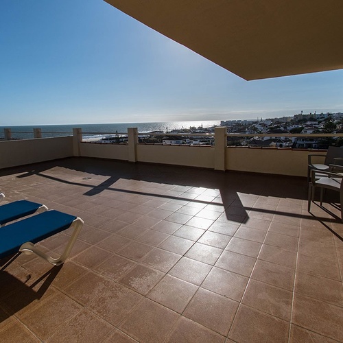 una terraza con sillas azules y una vista al océano