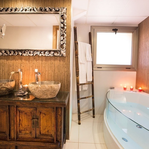 un baño con dos lavabos y una bañera con velas