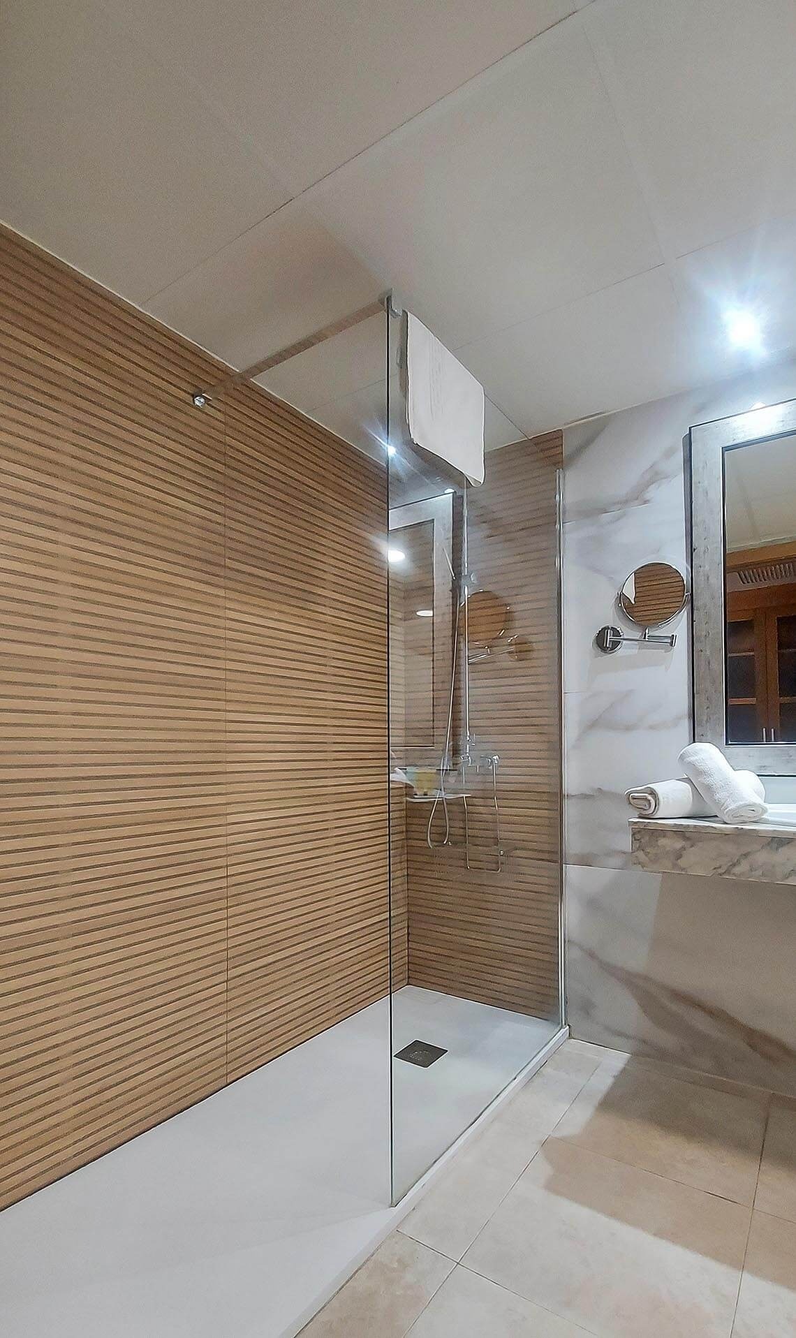 un baño con paredes de madera y una ducha de vidrio