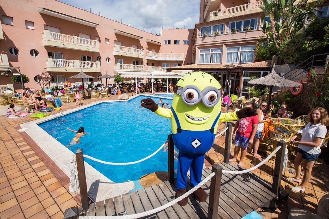 a minion mascot stands in front of a swimming pool