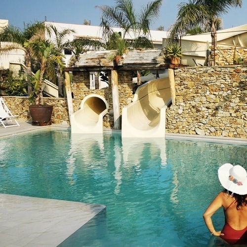 una mujer se sienta en la piscina con toboganes en el fondo