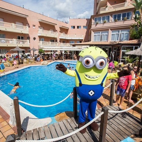 una mascota minion está parada en un muelle frente a una piscina