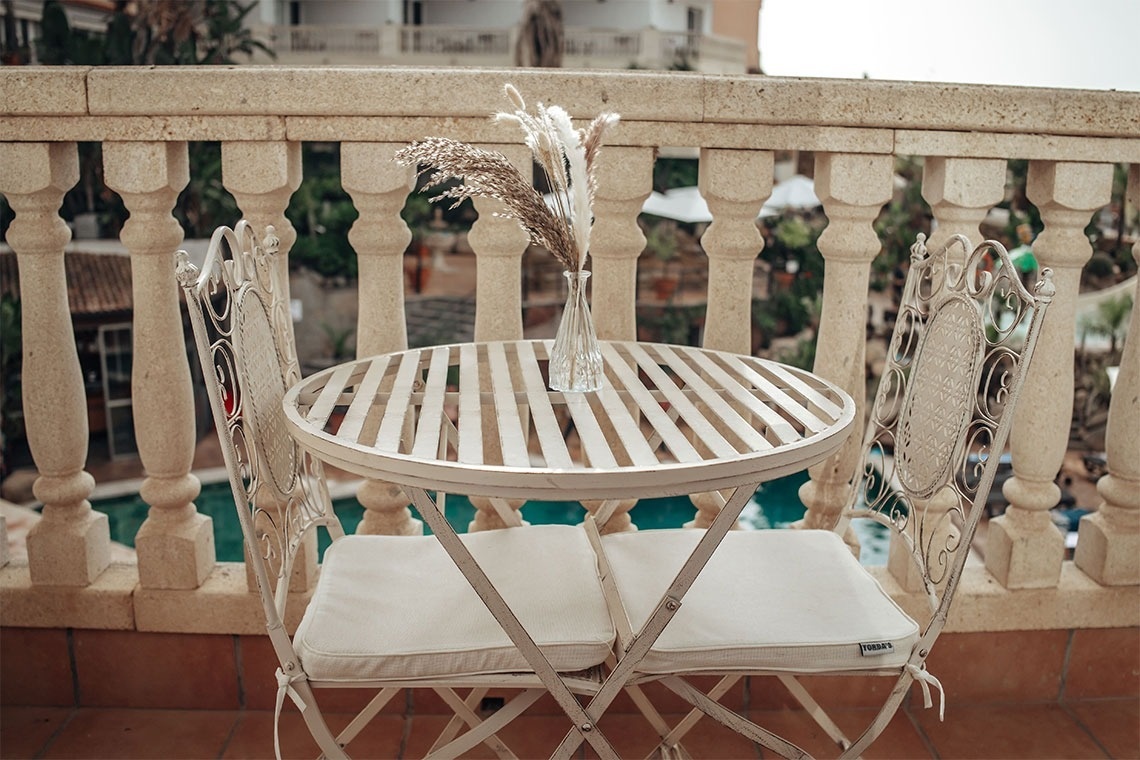 una mesa y dos sillas en un balcón junto a una piscina