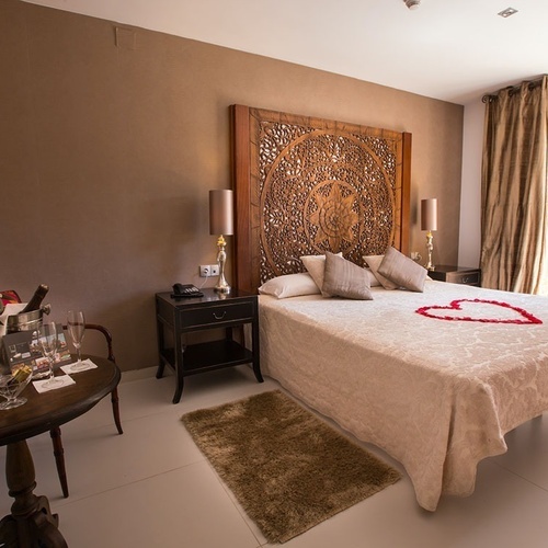 una habitación con una cama y una mesa con copas de vino