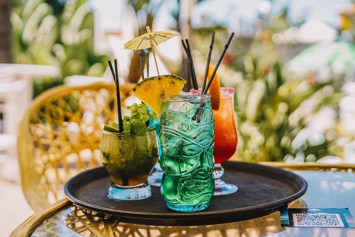 a tray of drinks including a blue one with a tiki head on it