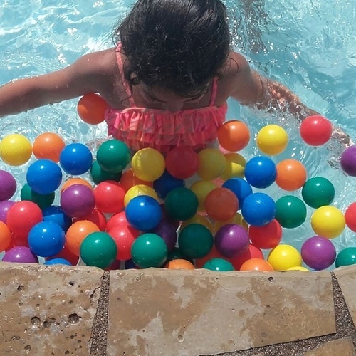 una niña nadando en una piscina llena de bolas de colores