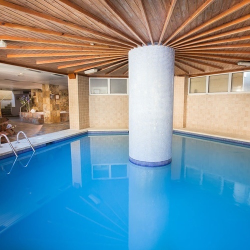 una piscina con un techo de madera y azulejos