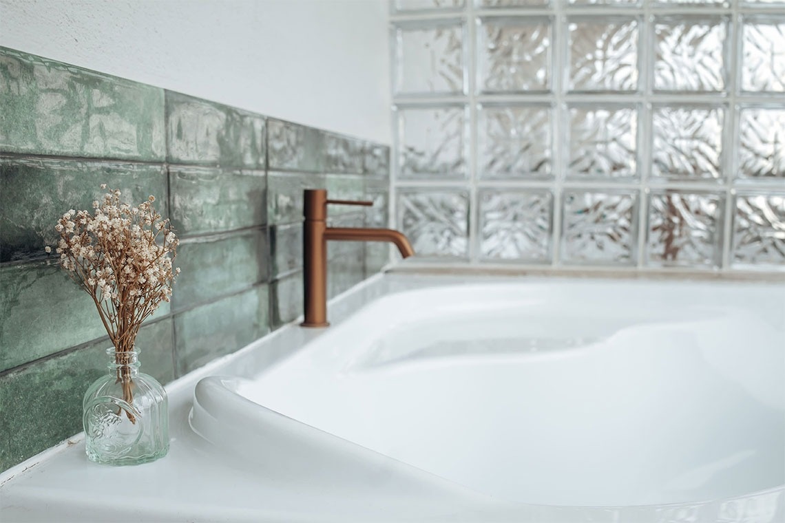 un jarrón de flores se encuentra en el borde de una bañera