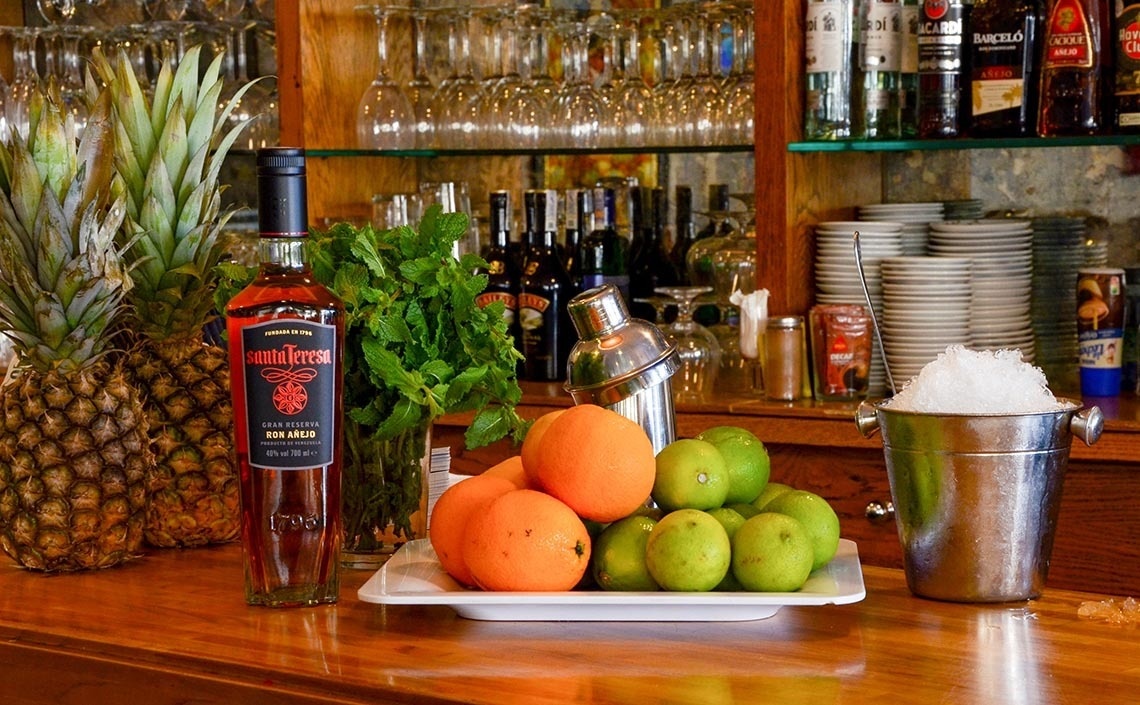 a bottle of rum sits on a bar next to fruit