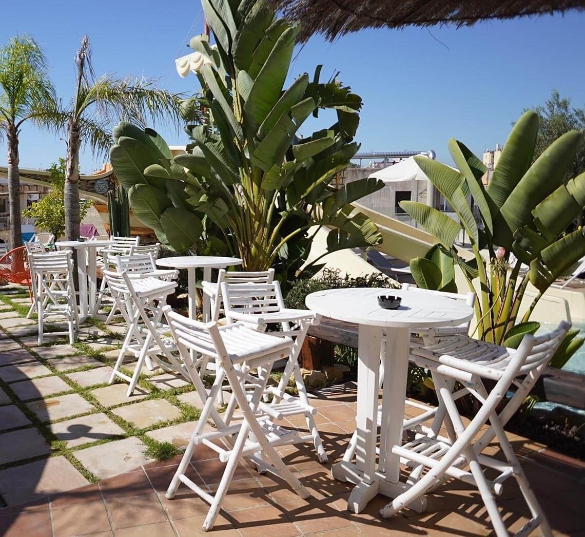 a row of white folding chairs and tables in a garden