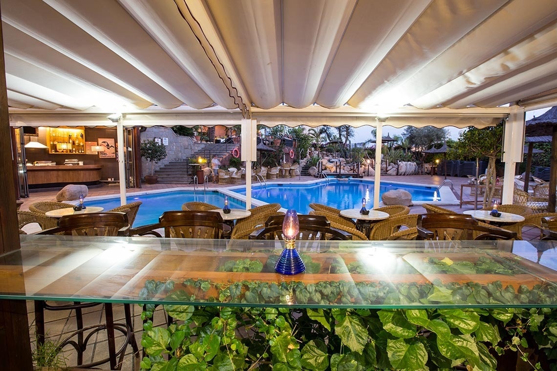 a swimming pool with tables and chairs in front of it