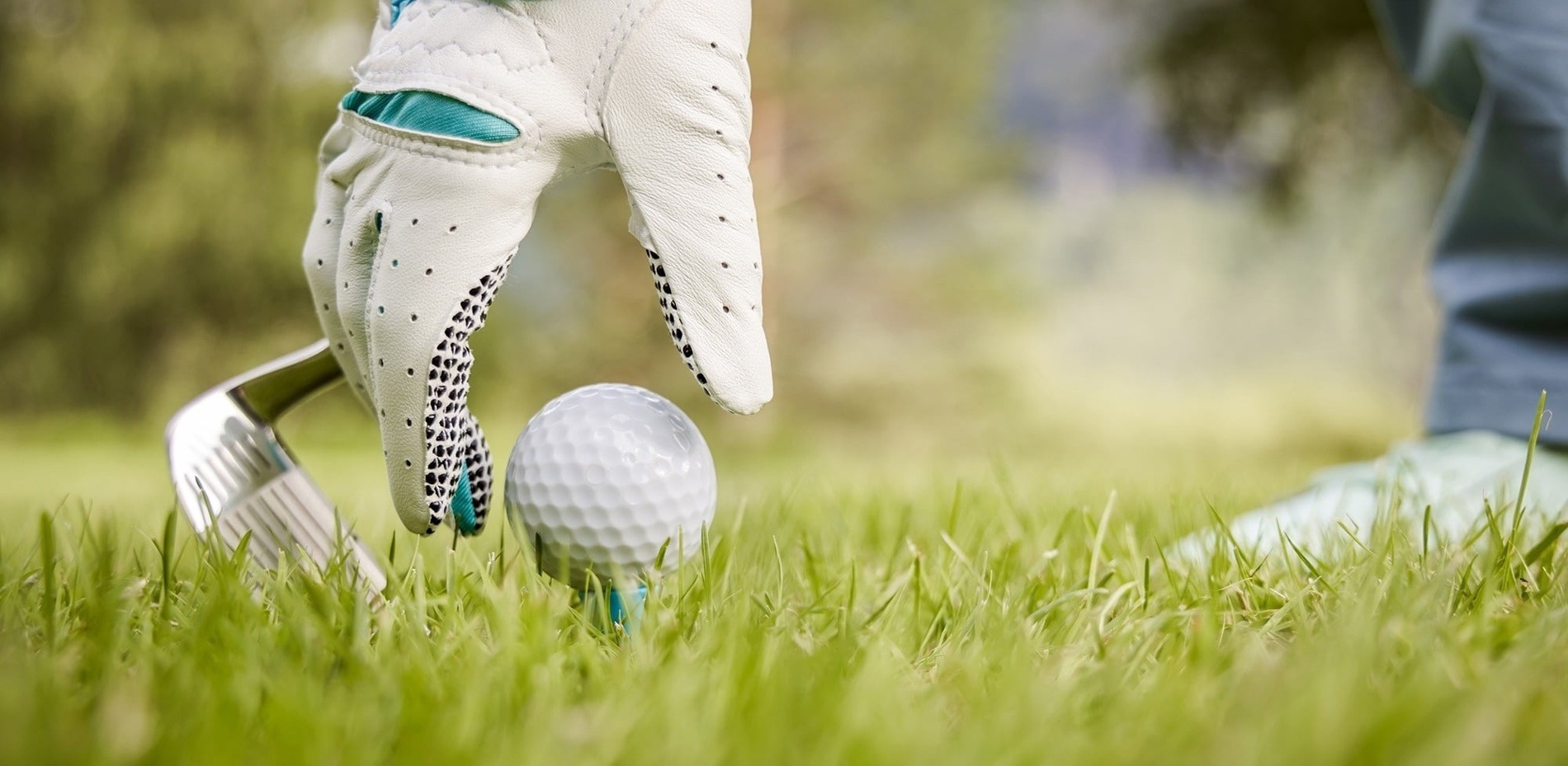 Ein Golfplatz mit prominenten Sandbunkern und saftigem Grün, umgeben von Bäumen und Bergen, unter einem strahlend blauen Himmel.