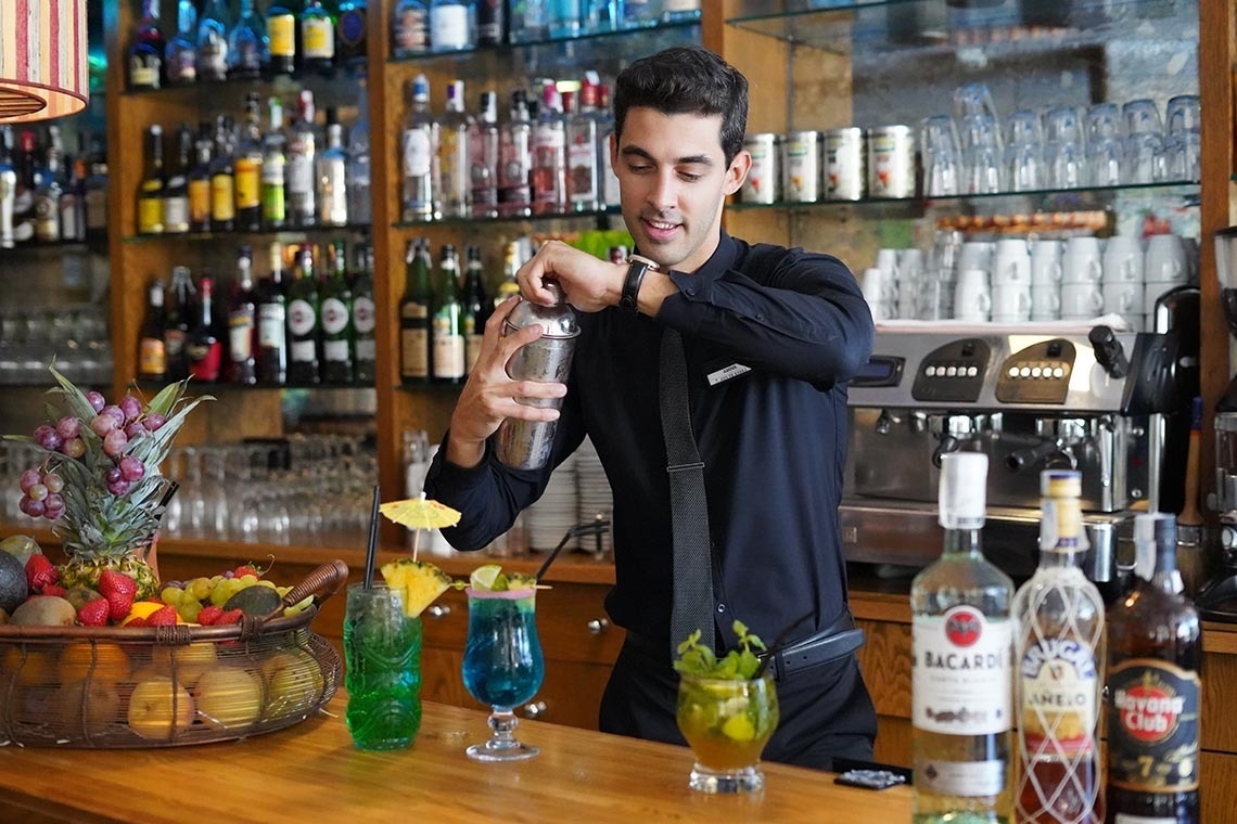 a bartender prepares a drink in front of a bottle of bacardi