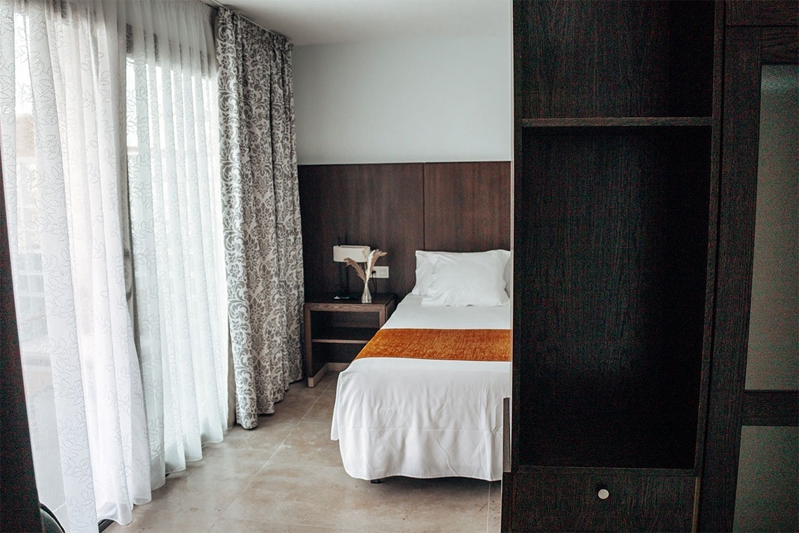 una habitación con una cama y una ventana con cortinas blancas